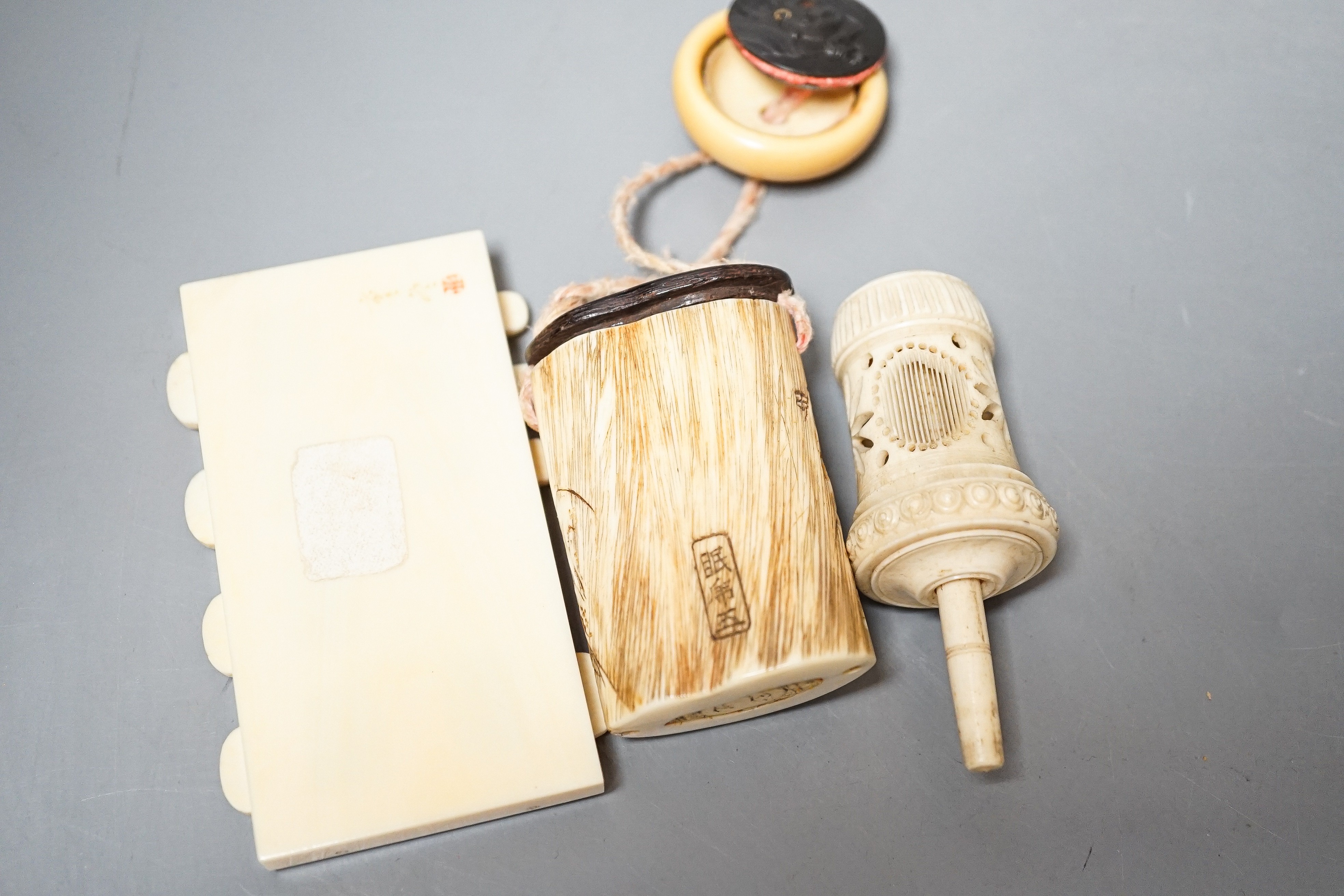 Three Japanese Ivory figures of men, a similar bezique marker, a Japanese staghorn single section inro with ivory manju, a Chinese ivory carving and a bone needlework container
